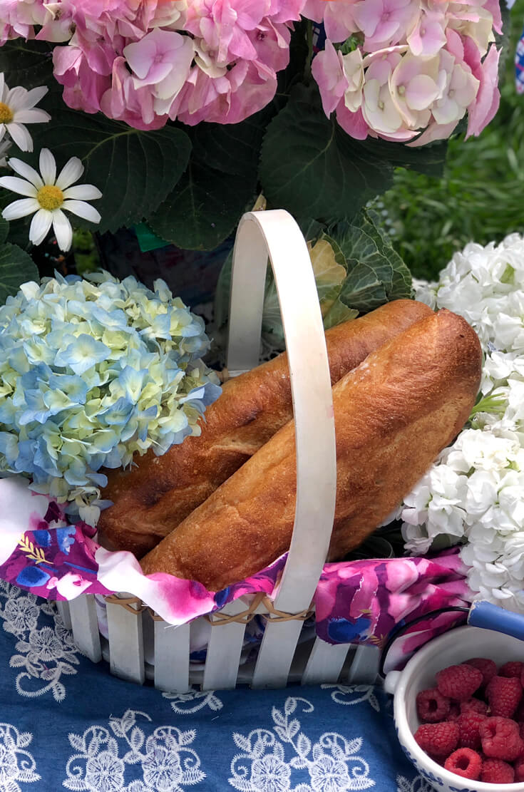 Basket with flowers and baguettes for summer picnic party