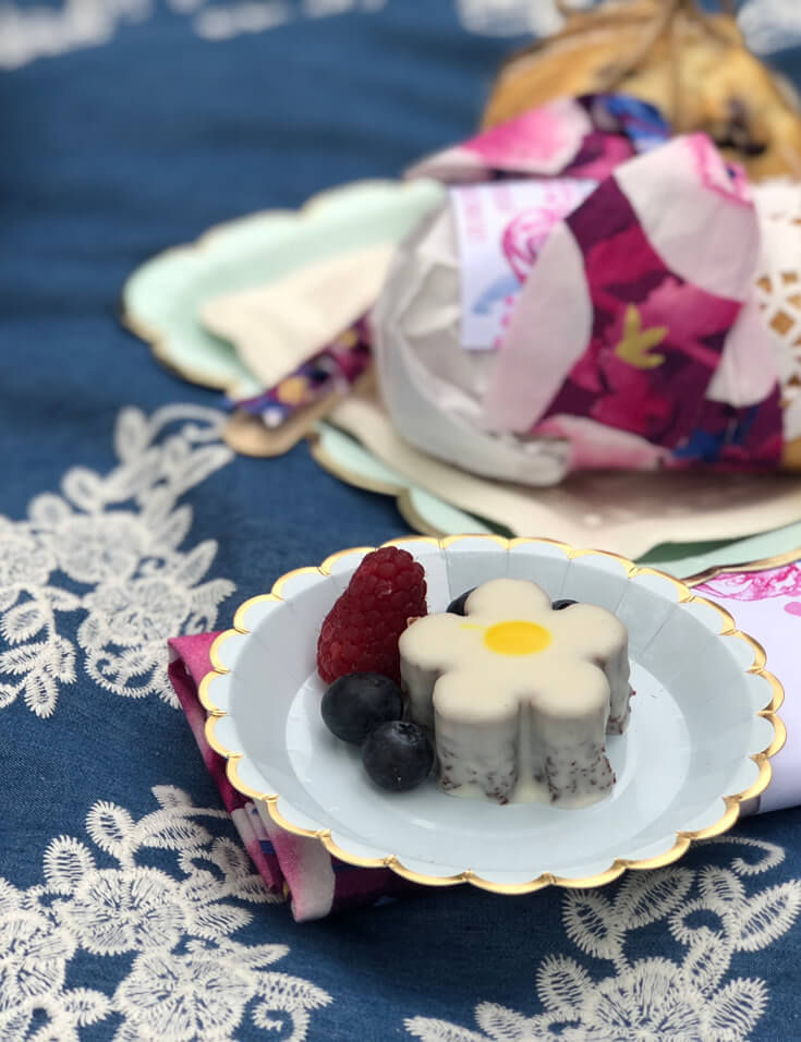 Plate of berries and chocolate flower treat on blanket for a charming summer picnic party